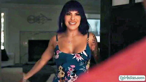 Tattooed busty trans babe smiling seductively in low-cut floral dress showing deep cleavage