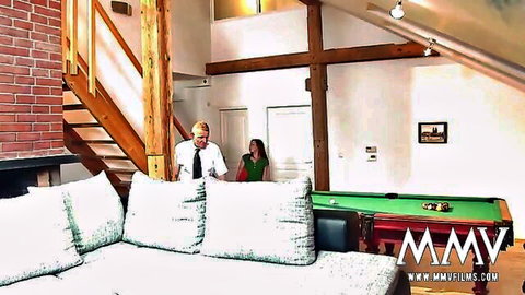 Suited blonde guy approaches woman in green dress near pool table in loft