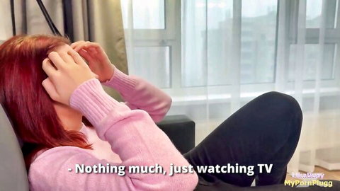 Redhead MyPornPlugg covers face on couch in pink sweater watching TV