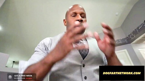 Bald black man in gray vest gesturing emphatically for Dogfart Network interracial porn promo