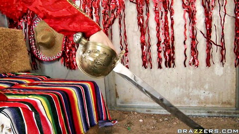 Hand in red pirate uniform gripping golden sword with sombrero and serape in Brazzers themed room