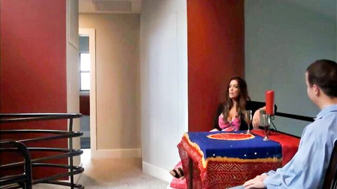 Sexy Indian woman in pink dress sits at table with microphone interviewed by man