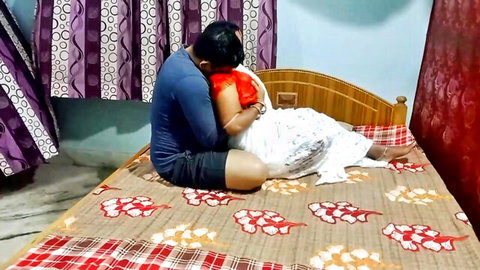Indian couple in sensual bedroom embrace, man hugging busty wife in white saree from behind
