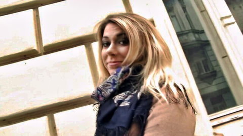 Blonde MILF in scarf and jacket smiling seductively outdoors