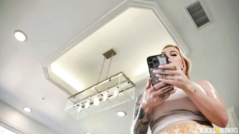 Tattooed blonde with huge tits in low-cut tank top takes pouty cleavage selfie