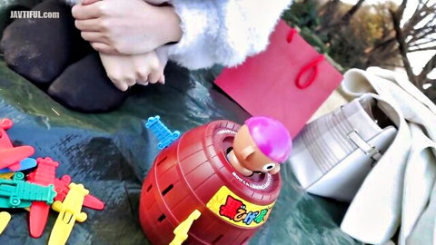 Elegant Asian lady in fuzzy white sweater plays with toys outdoors, feet visible