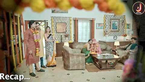 Indian couple in wedding garlands with family in sarees and kurtas in living room scene