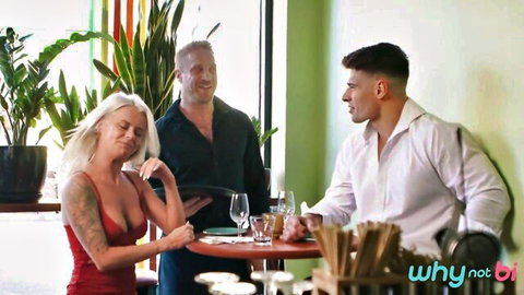 Tattooed blonde in tight red dress with huge cleavage sits distressed with two handsome men at dinner table