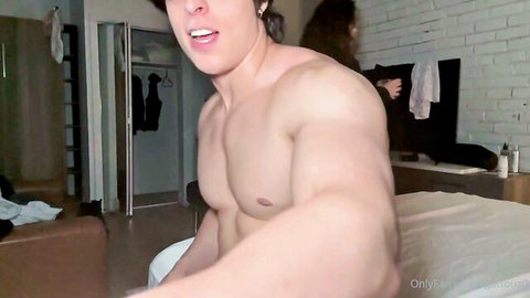 Muscular shirtless hunk with hat moans in pleasure as curvy babe stands behind him in bedroom