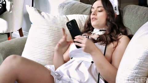 Sophia Burns in revealing white maid dress, lounging seductively on couch