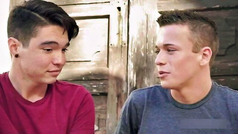 Two young gay guys in tight shirts staring intensely at each other face-to-face
