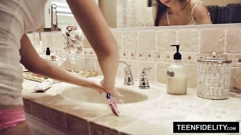 Alyce Anderson in white tank top and pink panties at sink, teasing bathroom view