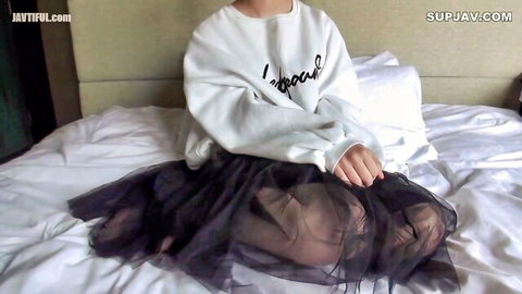 Young Asian babe sits on bed in oversized 'I love' sweatshirt and sheer black tulle skirt teasing her thighs