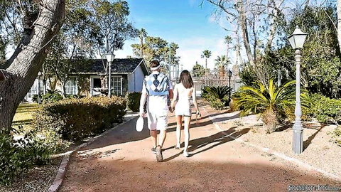 Petite woman in white dress walks with stud outdoors