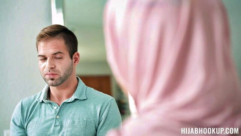 Handsome man in polo gazes intently at pink hijab woman from behind