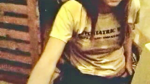 Petite brunette teen smiles teasingly through wooden slats in tight yellow Dynasty top