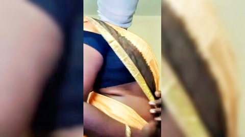 Sexy Indian Tamil aunty in yellow sari exposing midriff and curves