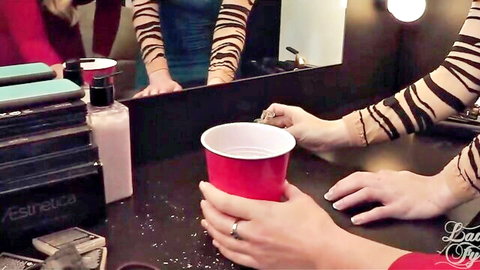 Sexy tiger-striped arms holding red solo cup spilling white powder in steamy dressing room