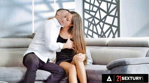 Renato embraces busty Lara Lee in tight black dress on couch