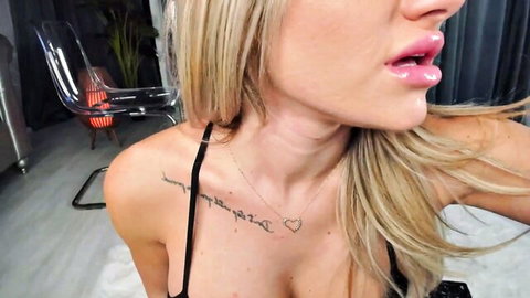 Blonde babe with huge tits, tattoos and glossy puckered lips teases cleavage