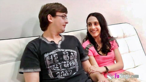 Young brunette couple on couch, girlfriend smiling intimately with boyfriend