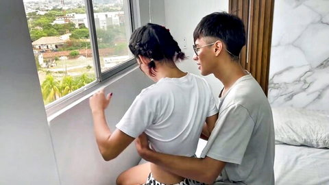 Asian couple in intimate embrace by window, teasing view from behind