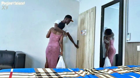 Ebony MILF in pink dress hugged from behind by man at door, amateur tease