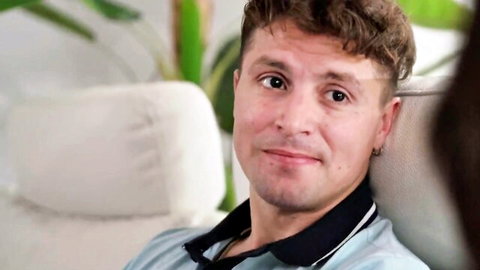 Smirking brunette guy in polo shirt lounging seductively on couch before hot fuck