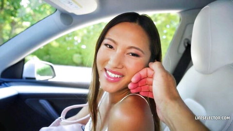 Petite Asian girl smiling in car with deep cleavage as man's hand grips her face roughly