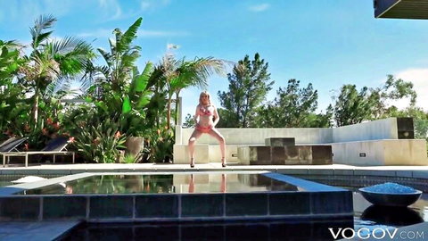 Blonde babe in skimpy pink bikini squats wide spreading legs teasing big tits and pussy mound poolside