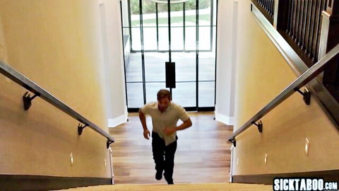 Balding man in white t-shirt and pants running up wooden stairs in modern home