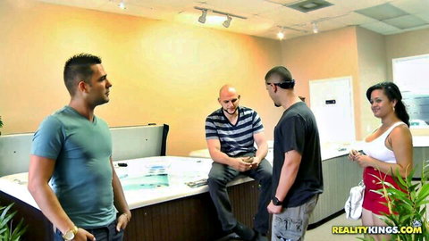 Katie Banks surrounded by three guys in steamy office tease