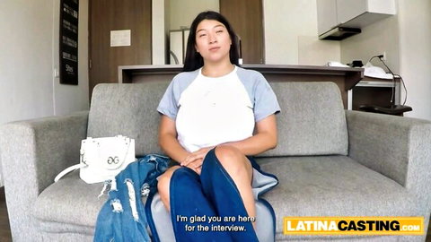 Busty Asian Latina in casual casting interview, smiling on couch