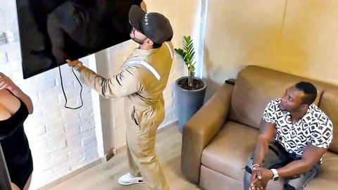 Busty wife in black dress watches interracial technician install TV