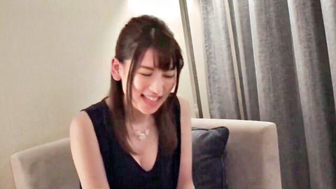 Smiling Japanese babe in hotel chair with deep cleavage and perky tits