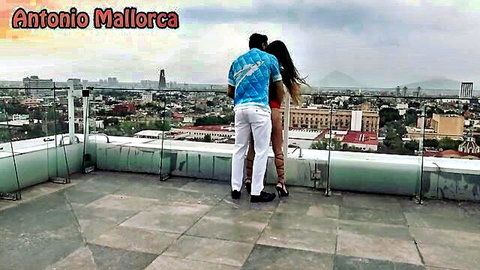 Antonio Mallorca embracing hot Venezuelan teen in red dress on penthouse rooftop