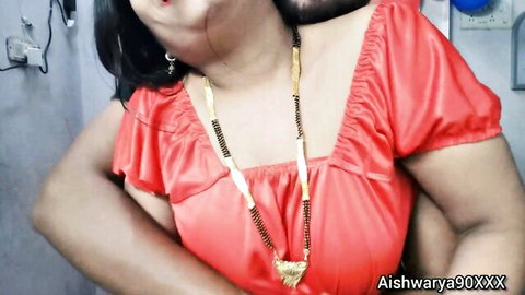 Desi Aishwarya in red dress passionately embraced by Indian man from behind