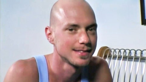 Muscular bald white hunk in tight tank top smiling seductively