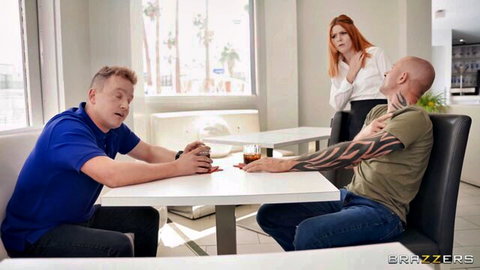 Redhead in white blouse stands behind two men at table in tense scene
