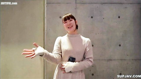 Smiling Asian babe in cozy sweater dress hiding secret desires