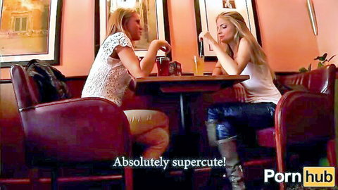 Two sexy blondes in tight tops chatting intimately at a bar table