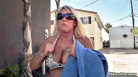 Busty blonde MILF Taelor in snake-print bikini top, showing deep cleavage outdoors