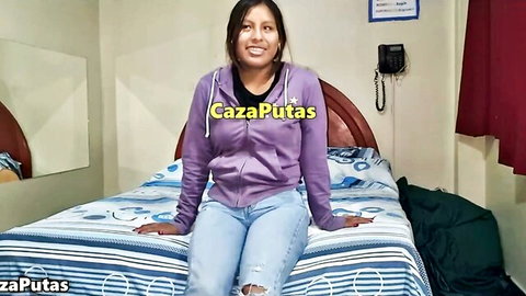 Smiling Latina teen in purple hoodie and jeans on bed for fake audition