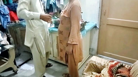 South Asian couple in shalwar kameez standing close in laundry room with washing machine