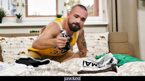 Muscular bearded hunk in Lakers tank top holds massive black dildo on bed