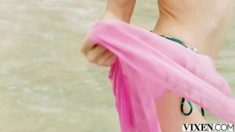 Skinny topless blonde babe teasing with pink sarong lifted on beach in green bikini bottoms