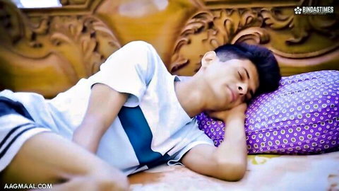 Young Indian man asleep on bed in white t-shirt and blue shorts