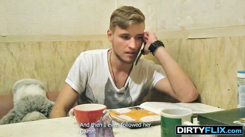 Young blonde man in tank top on phone at table, casual Dirtyflix scene