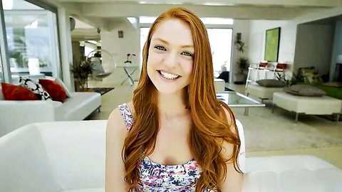 Smiling young redhead with small tits and long hair in floral tank top on couch