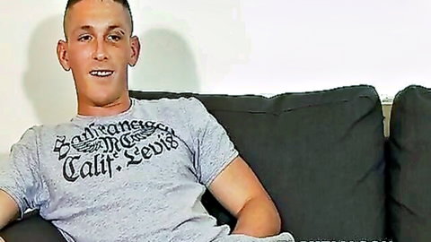 Muscular British guy in t-shirt smiles on couch solo preview
